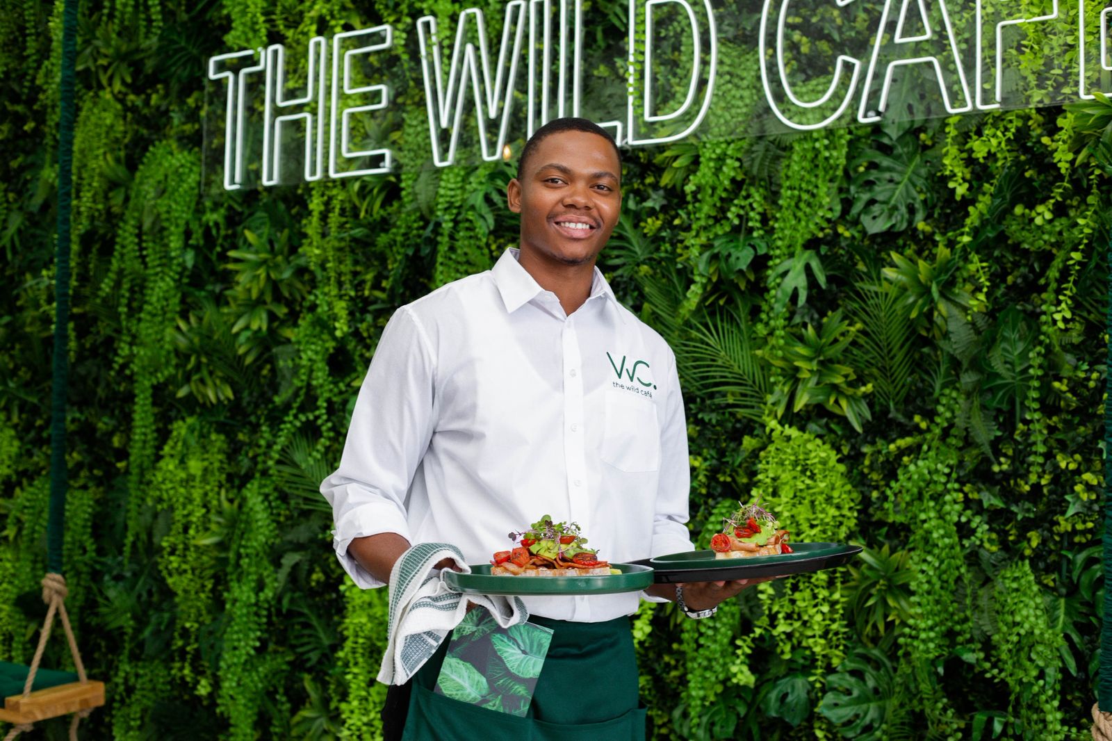 Wild Café staff member presenting a dish